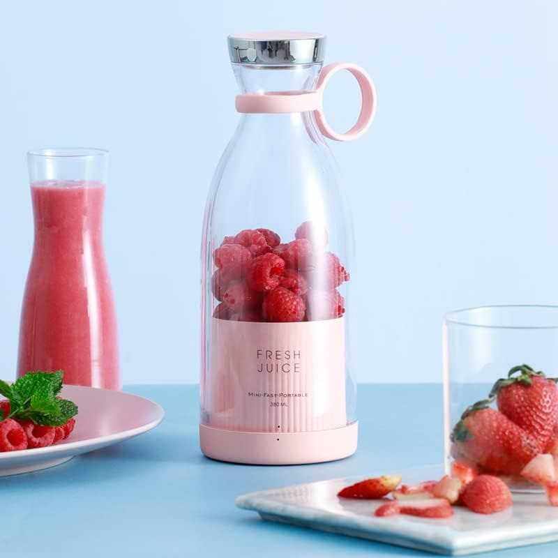 Portable blender with fresh juice and fruits on a table, ideal for smoothies and travel use.