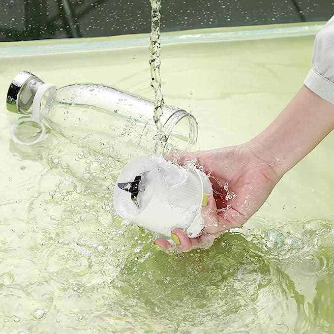 Portable blender being washed under running water for easy cleaning.